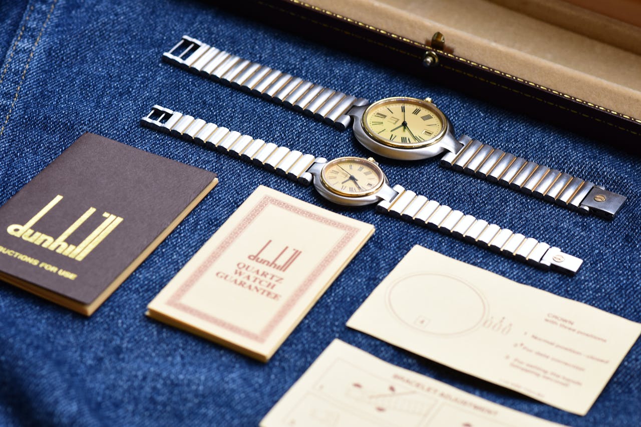 Vintage Dunhill watches with manuals and documents laid on denim for a classic look.